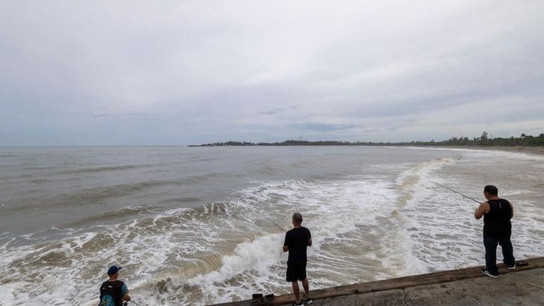 People fish along the shore in Arecibo, Puerto Rico, as Hurricane Erin brings rains to the island Sunday. The major storm will impact Long Island this week.